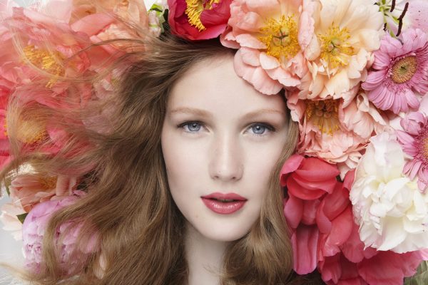 beauty shot of a brunette wearing professional hair and make-up between pink flowers