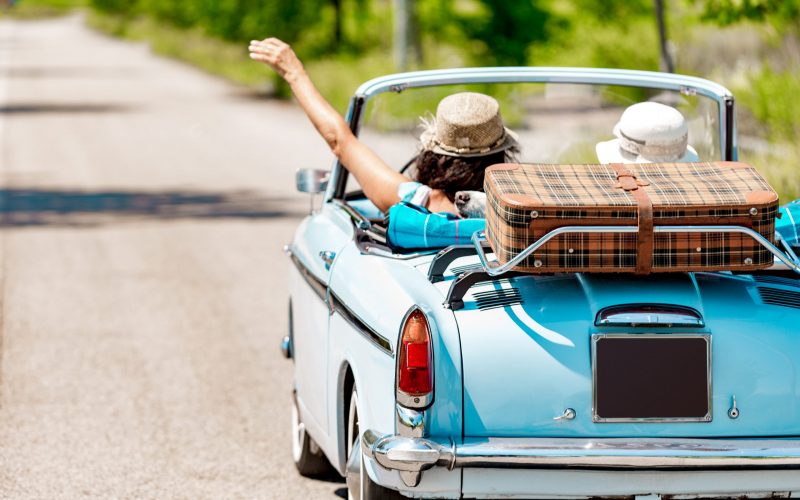 Happy Mature Couple portrait on a Road trip Vacation driving a Vintage car